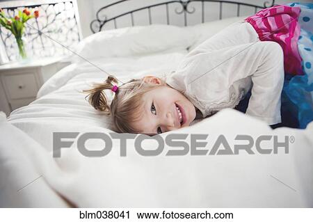 Smiling girl playing on bed View Large Photo Image Stock Image - Smiling girl playing on bed. Fotosearch