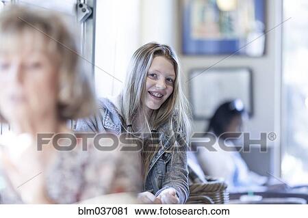Stock Image - Smiling girl sitting in waiting area. Fotosearch