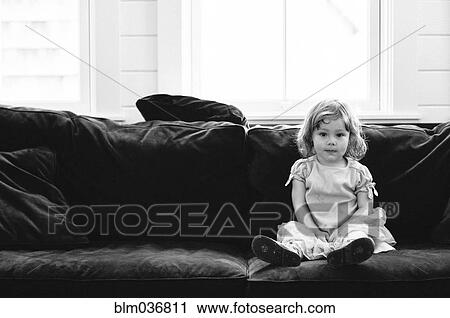 Stock Image - Smiling girl sitting on sofa. Fotosearch