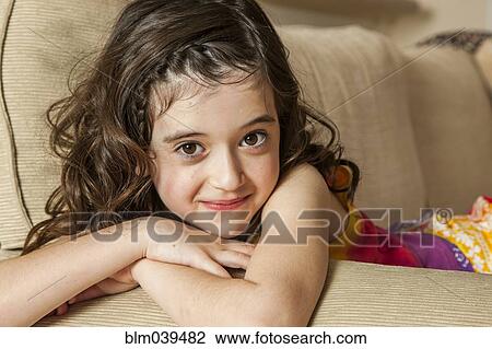 Smiling girl sitting on sofa View Large Photo Image Stock Image - Smiling girl sitting on sofa. Fotosearch