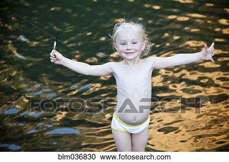 Smiling girl standing with arms outstretched at lake View Large Photo Image Stock Image - Smiling girl standing with arms outstretched at lake. Fotosearch