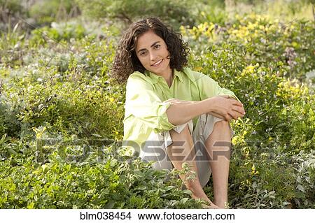 Smiling Hispanic woman sitting in garden View Large Photo Image Picture - Smiling Hispanic woman sitting in garden. Fotosearch