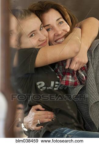 Stock Photo - Smiling mother and daughter hugging in mirror. Fotosearch