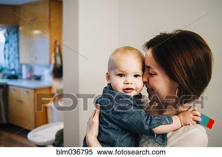 Stock Photography - Smiling mother nuzzling son in kitchen. Fotosearch