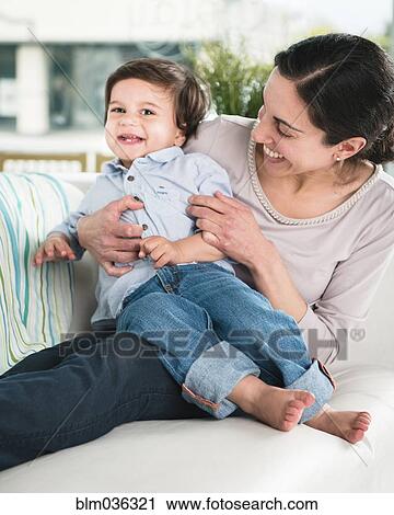 Smiling mother tickling son on sofa View Large Photo Image Stock Image - Smiling mother tickling son on sofa. Fotosearch
