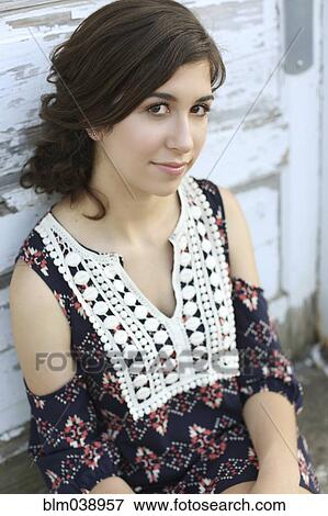 Stock Photo - Smiling teenage girl leaning on wooden wall. Fotosearch