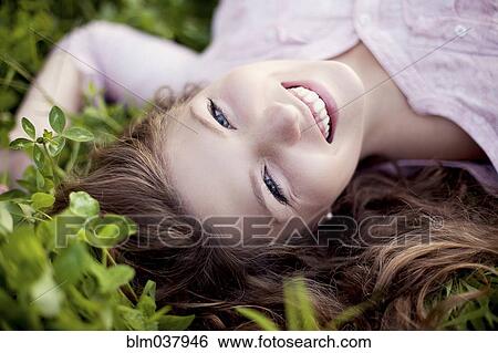 Smiling woman laying in grass View Large Photo Image Stock Photograph - Smiling woman laying in grass. Fotosearch