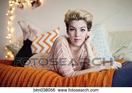 Stock Photograph - Smiling woman laying on bed. Fotosearch
