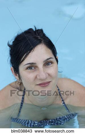 Stock Image - Smiling woman swimming in pool. Fotosearch