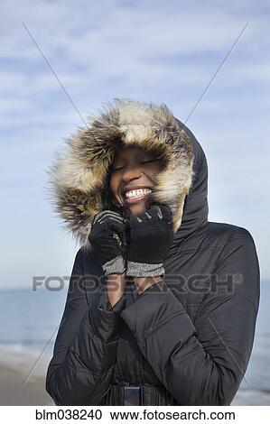 Smiling woman wearing coat on beach View Large Photo Image Stock Image - Smiling woman wearing coat on beach. Fotosearch