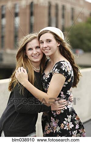 Stock Image - Smiling women hugging on urban rooftop. Fotosearch