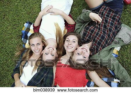 Stock Photo - Smiling women laying on blanket in grass. Fotosearch