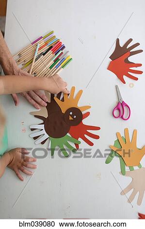 Stock Image - Students and teacher making Thanksgiving turkey crafts in classroom. Fotosearch