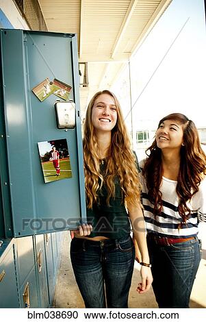 Stock Image - Students standing by decorated locker at high school. Fotosearch