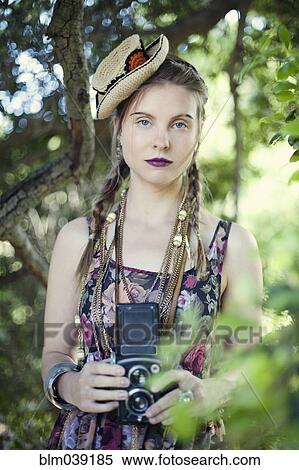 Stock Photography - Stylish woman photographing with vintage camera. Fotosearch
