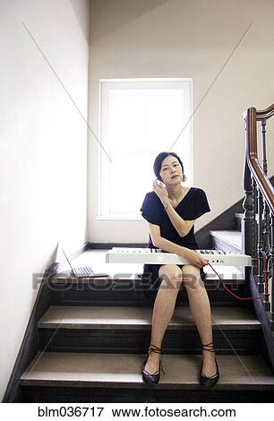 Stock Photo - Taiwanese woman playing keyboard on staircase. Fotosearch