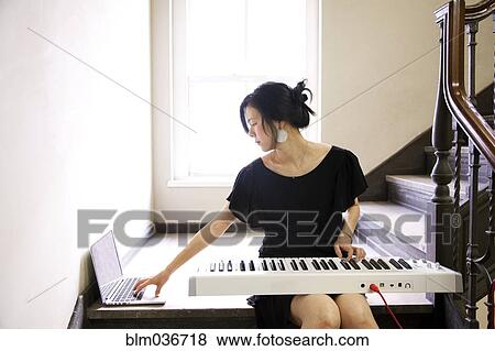 Stock Photo - Taiwanese woman playing keyboard on staircase. Fotosearch