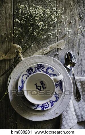 Stock Image - Teacup, saucers and dried flowers on table. Fotosearch