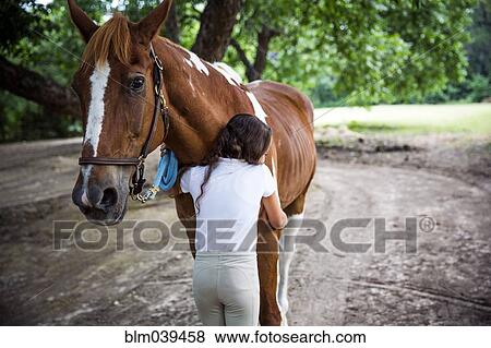 Stock Photo - Teenage girl hugging horse in field. Fotosearch