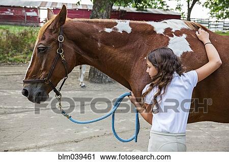 Stock Image - Teenage girl hugging horse on ranch. Fotosearch