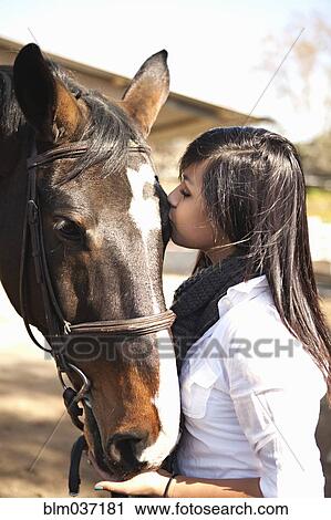 Teenage girl kissing horse in stable View Large Photo Image Stock Image - Teenage girl kissing horse in stable. Fotosearch