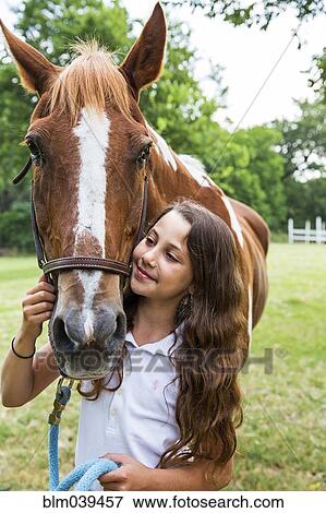 Stock Photo - Teenage girl leading horse in field. Fotosearch