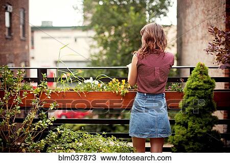 Stock Image - Teenage girl looking out from urban rooftop. Fotosearch