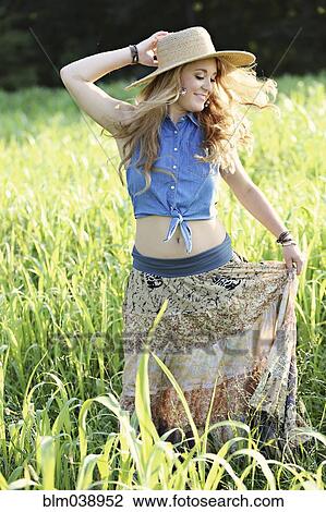 Stock Image - Teenage girl playing in tall grass. Fotosearch