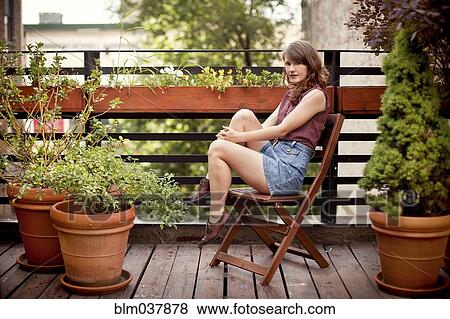 Stock Photo - Teenage girl sitting on urban rooftop. Fotosearch