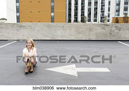 Teenage girl sitting on urban rooftop parking lot View Large Photo Image Stock Photograph - Teenage girl sitting on urban rooftop parking lot. Fotosearch