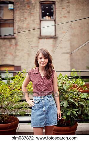 Stock Image - Teenage girl standing on urban rooftop. Fotosearch