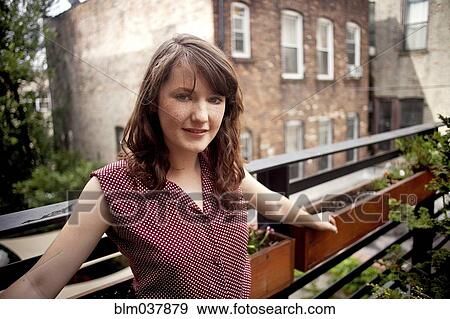 Stock Photo - Teenage girl standing on urban rooftop. Fotosearch