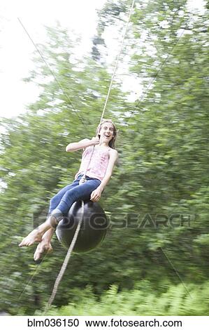 Teenage girl swinging on rope swing View Large Photo Image Stock Image - Teenage girl swinging on rope swing. Fotosearch