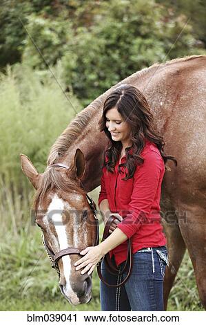 Stock Image - Teenage girl walking horse in rural field. Fotosearch