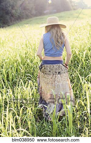 Stock Image - Teenage girl walking in tall grass. Fotosearch