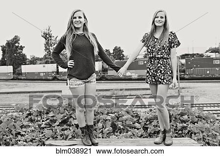 Stock Image - Teenage girls holding hands in train yard. Fotosearch
