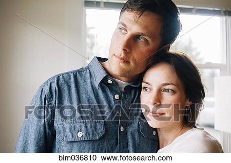 Stock Image - Thoughtful couple hugging near window. Fotosearch