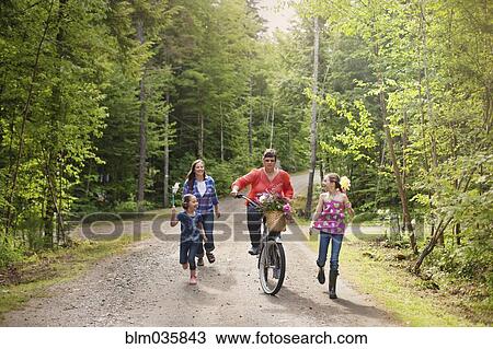 Stock Image - Three generations of Caucasian women walking on dirt road. Fotosearch
