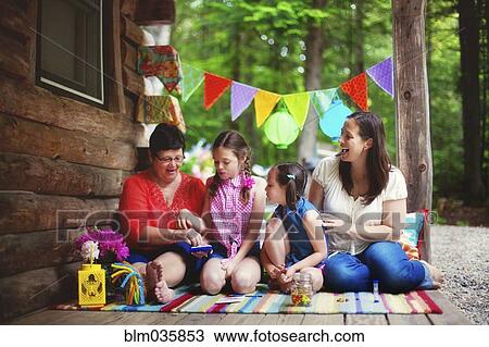 Stock Image - Three generations of Caucasian women playing with toy on cabin porch. Fotosearch
