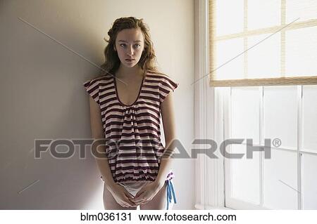 Timid woman standing near window View Large Photo Image Stock Image - Timid woman standing near window. Fotosearch