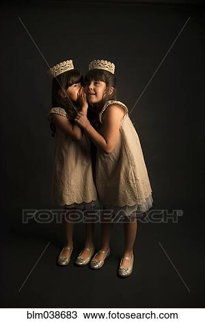 Whispering twin girls wearing crowns and princess costumes View Large Photo Image Stock Image - Whispering twin girls wearing crowns and princess costumes. Fotosearch