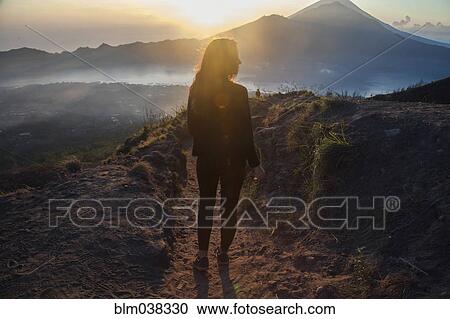 Stock Image - Woman admiring rural landscape from mountain path. Fotosearch