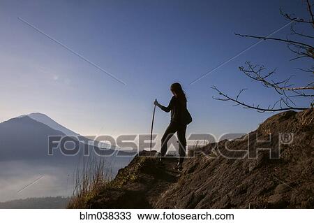Stock Image - Woman admiring rural landscape from mountain path. Fotosearch