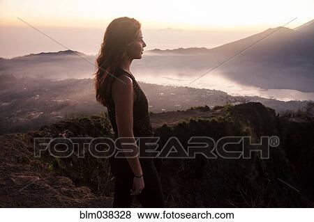 Stock Photo - Woman admiring rural landscape from mountaintop. Fotosearch