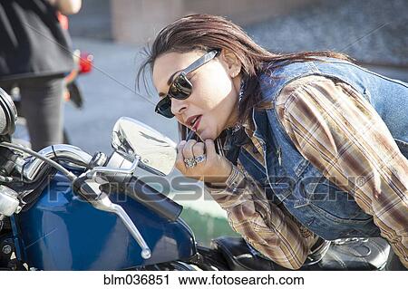 Stock Image - Woman applying makeup in motorcycle mirror. Fotosearch