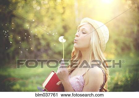 Woman blowing dandelion seeds in rural field View Large Photo Image Stock Image - Woman blowing dandelion seeds in rural field. Fotosearch