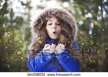 Stock Image - Woman blowing glitter from hands. Fotosearch