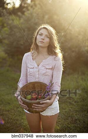 Woman carrying bucket of apples in field View Large Photo Image Stock Photo - Woman carrying bucket of apples in field. Fotosearch