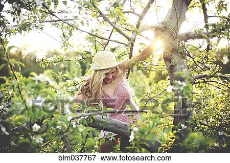 Stock Photo - Woman climbing flowering tree. Fotosearch