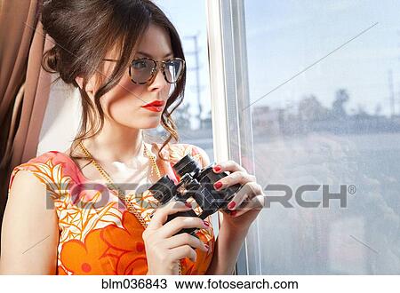 Woman holding binoculars at window View Large Photo Image Stock Image - Woman holding binoculars at window. Fotosearch
